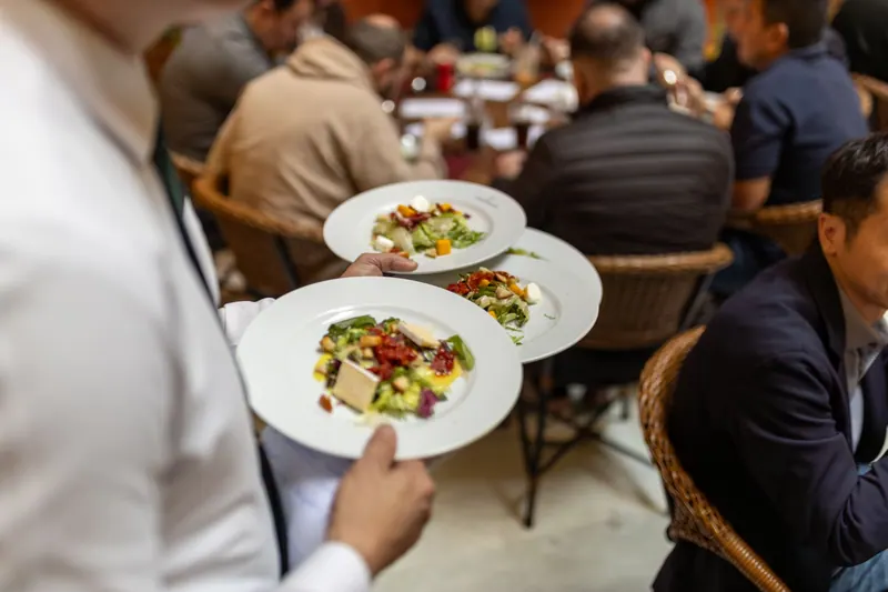 Servicekraft bringt Essen an einen Restauranttisch